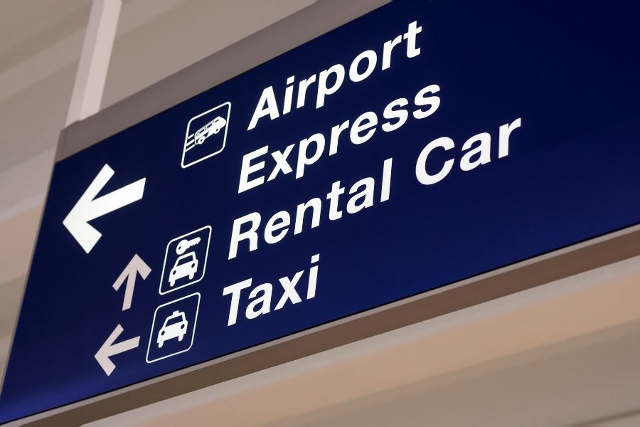Traveler picking up a rental car with luggage and car keys