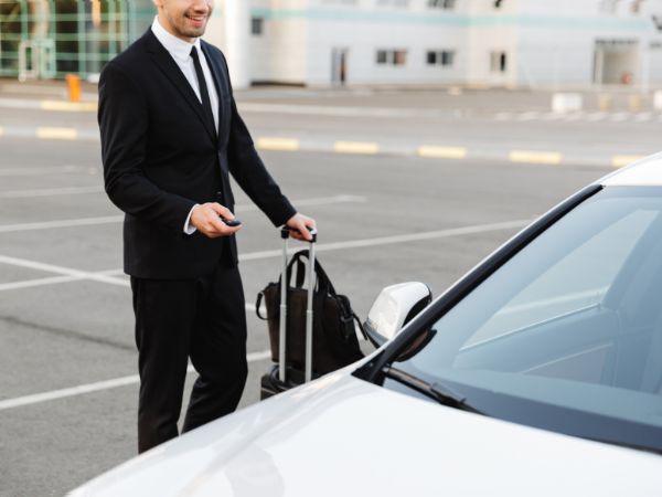 Traveler picking up a rental car with luggage and car keys